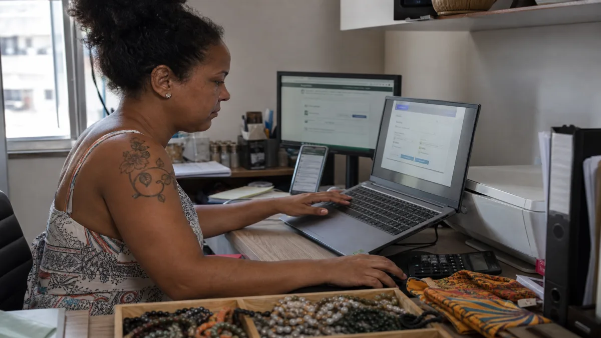 Microempreendedora emitindo nota fiscal no notebook, com documentos e acessórios em mesa, refletindo a reforma tributária