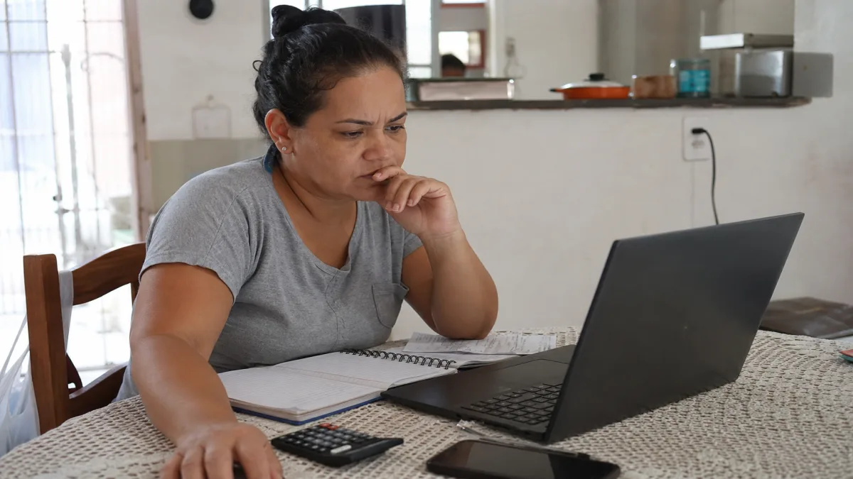 MEI com DAS atrasado: Microempreendedora analisa portal oficial do MEI no notebook, verificando DAS atrasado e a.