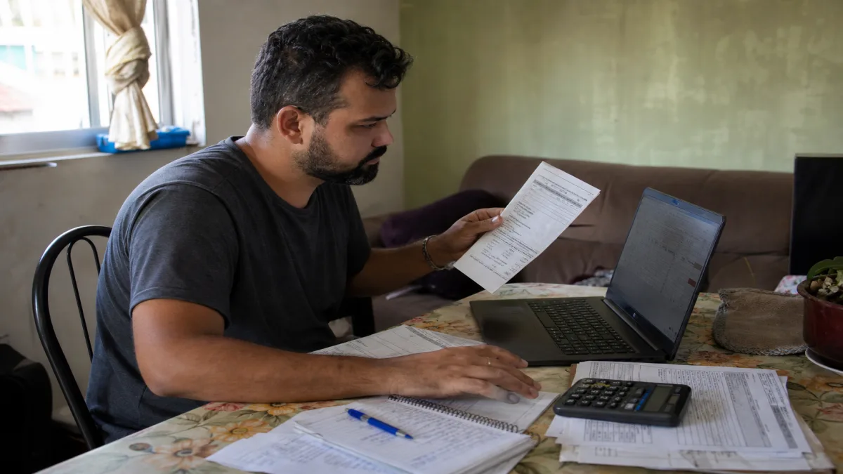 Microempreendedor revisando documentos e utilizando computador para regularizar MEI em atraso